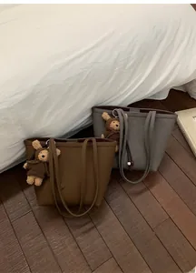 Detailed top view of textured faux leather tote bag with a cute plush bear pendant
