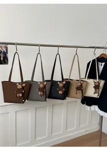Close-up of minimalist tote bags in five colors with cute plush bear charms on a rack