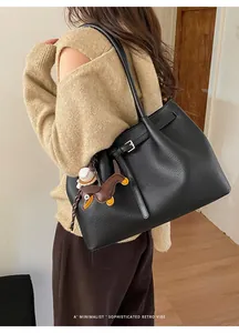 Detail der schwarzen Shopper-Tasche mit Lychee-Struktur und süßen Taschenanhängern
