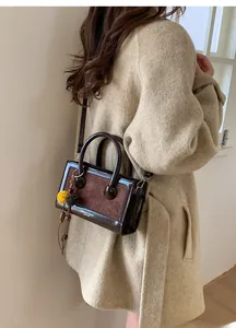 Détail du sac baguette marron foncé avec texture en daim et finitions en cuir brillant