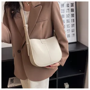 Détail d'un sac selle crème avec texture en cuir grainé et bandoulière réglable