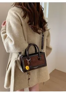 Détail du sac en cuir bicolore avec anneaux métalliques et breloque fleur jaune