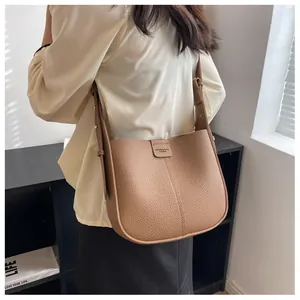 Sac seau en cuir grainé marron porté à l'épaule par un mannequin dans un décor de style