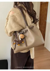 Detail der braunen Retro-Tote-Bag aus Leder mit Litschistruktur und Anhängern