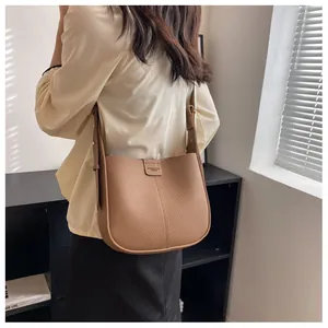Vue latérale du sac seau marron en cuir avec bandoulière réglable porté par le mannequin
