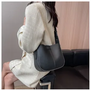 Détail du sac seau minimaliste en cuir grainé noir avec une large bandoulière élégante