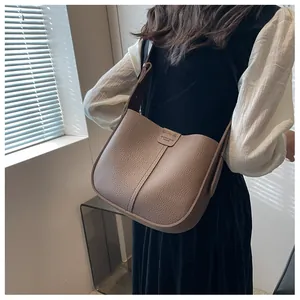 Détail du sac seau en cuir taupe montrant la texture fine et le logo embossé Arisuee