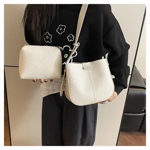 Détail du sac seau en cuir grainé crème et de sa pochette zippée assortie