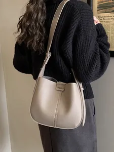 Sac seau minimaliste en cuir kaki avec étiquette de marque porté à l'épaule