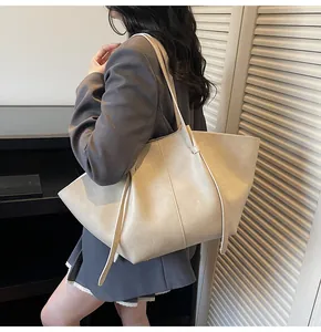 Vue latérale d'un grand sac cabas en cuir crème porté à l'épaule au style minimaliste