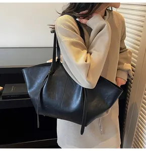 Détail d'un grand cabas en cuir noir avec texture grainée et bandoulière élégante