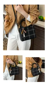 Detail view of the black and white plaid handbag with wooden bead charm and crossbody strap