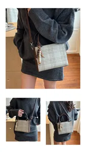 Detail of checkered crossbody bag with beaded pendant and adjustable strap on wood floor