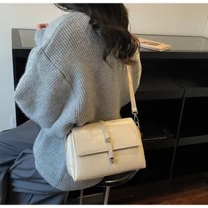 Mannequin portant un sac bandoulière crème rectangulaire avec boucle en métal fine