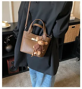Brown lychee texture bucket bag with silver clasp and plush bear charm on model