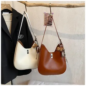 Détail de sacs Hobo crème et caramel avec pendentifs cœur sur une poutre en bois