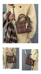 Detail of a dark brown checkered crossbody bag with vintage wooden beads decoration