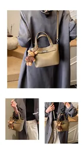 Detail of khaki bucket bag with textured leather, metal lock and cute bear charm pendant