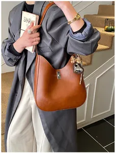 Détail d'un sac seau demi-lune en cuir marron avec fermoir argenté et breloque cœur léopard