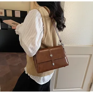 Gros plan d'un sac bandoulière rétro marron avec fermoir métallique argenté et texture cuir