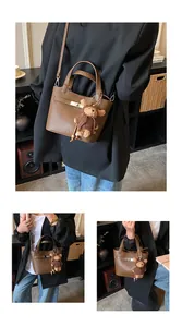 Detail of brown litchi pattern leather bucket bag with metal lock and bear charm