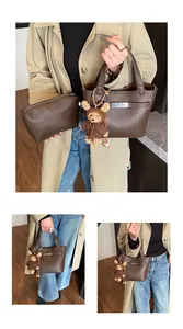 Detail of dark brown lychee leather bucket bag with silver lock and teddy bear charm