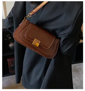 Detail einer braunen Vintage-Baguette-Tasche mit Goldverschluss auf schwarzem Blazer