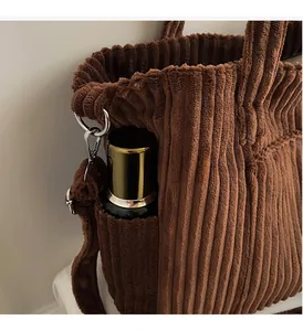 Detail of a brown corduroy tote bag showing a side pocket and embroidered TO B logo