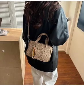 Détail du sac à main kaki avec texture tissée et breloque à perles élégante
