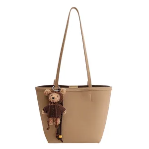 Khaki pebbled tote bag for women with chic teddy bear charm on white background