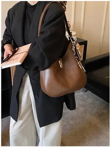 Détail du sac seau en cuir marron foncé avec fermoir rotatif argenté et foulard léopard