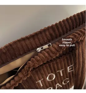 Detail of a dark brown corduroy tote bag showing smooth silver zipper and inner lining