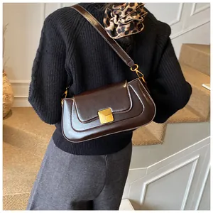 Detailansicht einer dunkelbraunen Lackleder-Baguette-Tasche mit goldener Metallschnalle