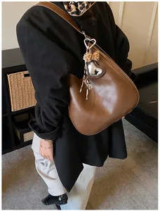 Détail du grand sac hobo marron avec breloque cœur et nœud léopard porté par un mannequin