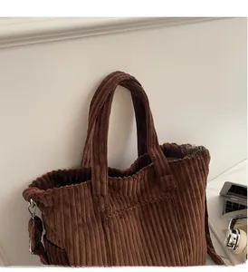 Detailed texture of dark brown corduroy tote bag with white embroidered logo