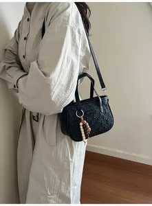 Détail du sac noir avec motifs d'ours gaufrés et breloque en perles de bois