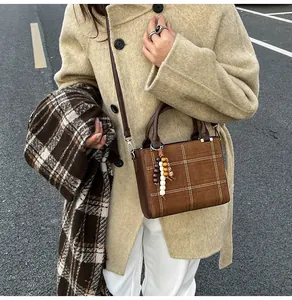 Detail of brown checkered crossbody bag with suede texture and wooden bead charm