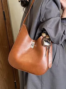 Sac seau classique en cuir marron caramel avec fermoir rotatif argenté et breloque
