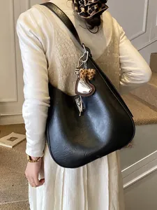 Sac seau élégant en cuir synthétique noir avec breloque cœur porté par un mannequin