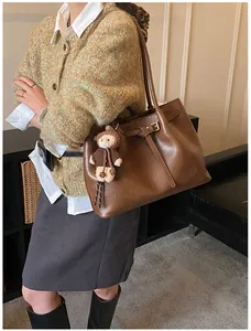Retro brown leather tote bag with slim straps and a cute bear charm on a female model