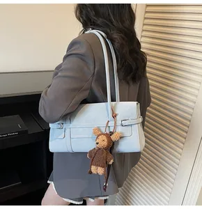 Detail of light blue shoulder bag with silver buckle and cute teddy bear charm accessory