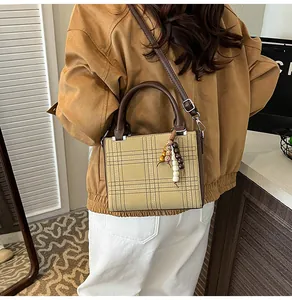 Close-up of minimalist khaki checkered crossbody bag with PU leather and bead charm detail