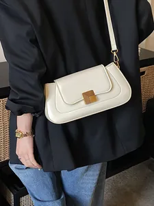 Schicke cremeweiße Baguette-Schultertasche mit goldener Schnalle auf schwarzem Blazer