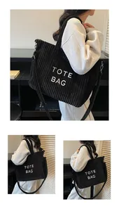 Detail of black corduroy tote bag showing ribbed texture and TOTE BAG lettering