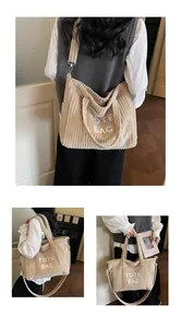 Detail of corduroy tote bag showing vertical texture, embroidery, and adjustable strap