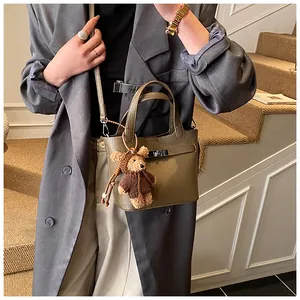 Detail of khaki leather mini bucket bag with teddy bear charm and silver twist lock