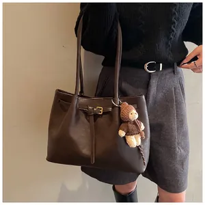 Detail of dark brown faux leather tote with buckle accent and cute teddy bear charm