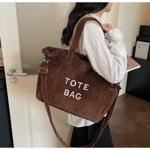 Detail of brown corduroy tote bag featuring TOTE BAG embroidery and adjustable strap