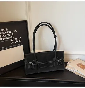 Detail of black suede shoulder bag featuring contrast white stitching and silver buckle accent