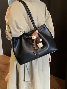 Minimalist black faux leather tote bag with shoulder straps and cute teddy bear charm